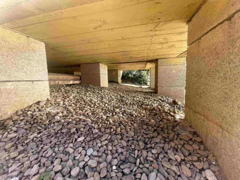 Konkrétní betonové patky pod dřevěnou konstrukcí s kamenivem.