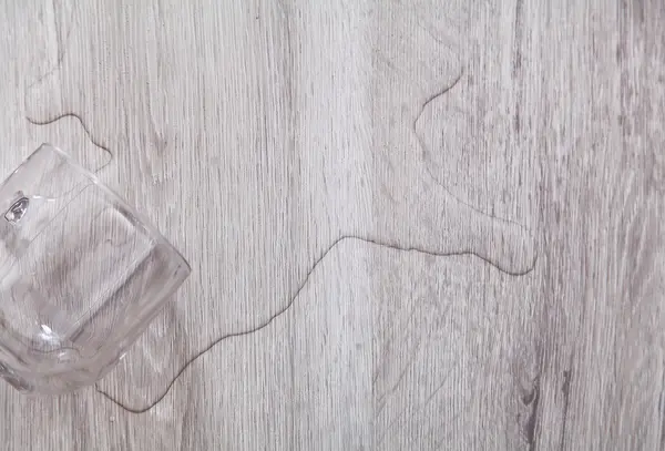 Voda z sklenice rozlitá na vinylové podlaze