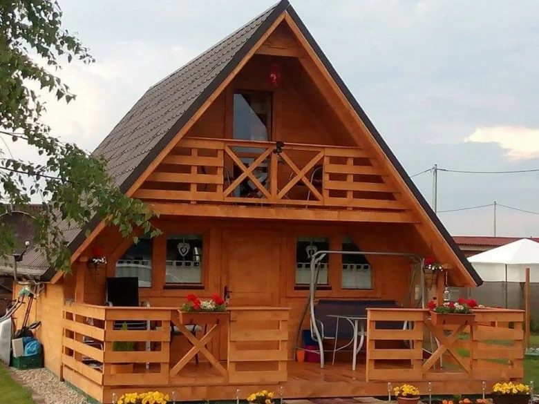 Dřevěná chata s terasou a balkónem po dokončení stavby.