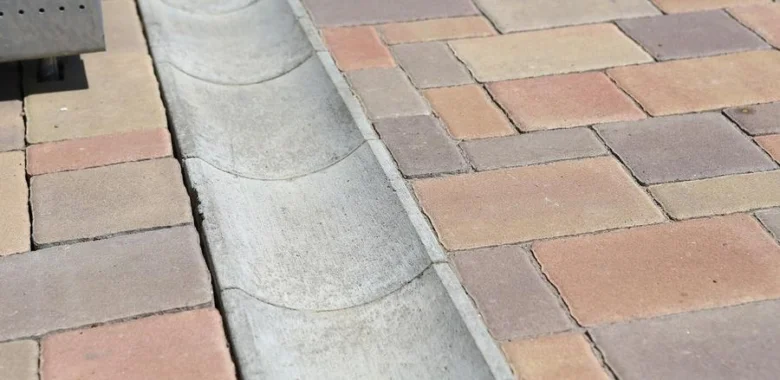 Konkrétní betonová drenážní rýha mezi dlaždicemi.