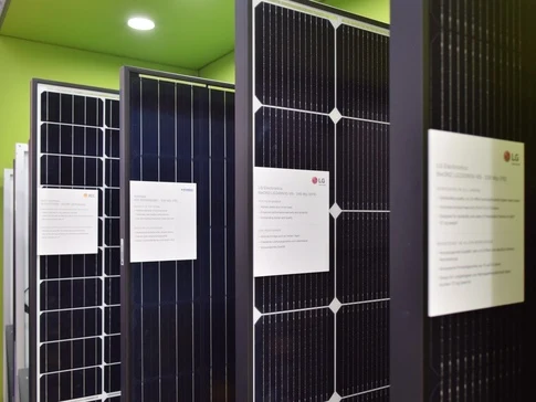 Výstava černých fotovoltaických modulů značky LG s informačními cedulemi.
