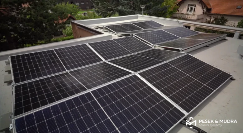 Fotovoltaické panely na střeše budovy v městském prostředí.