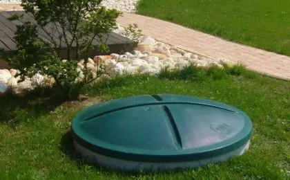 Zelená krytka domovní čistírny odpadních vod v trávníku.