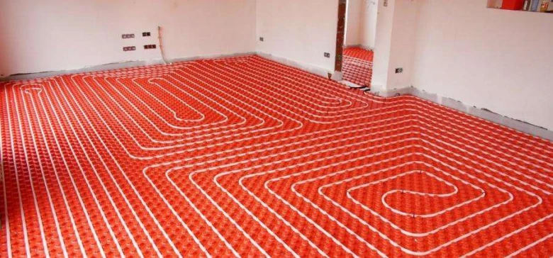 Instalace elektrického podlahového topení s červenými kabely v místnosti.