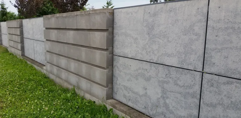 Řada betonových plotů s různými typy desek na trávníku.