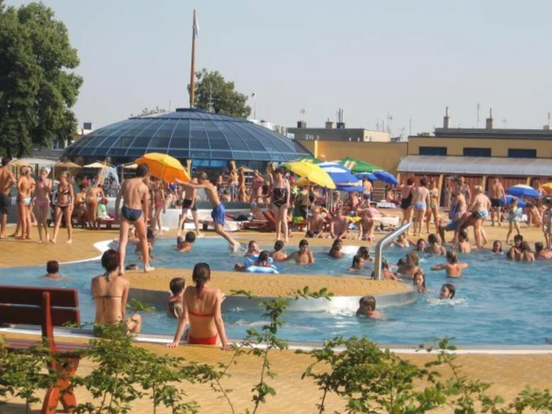 Lidé plavou a sluní se v bazénu na koupališti.