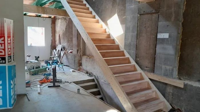 Stavební práce na dřevěném schodišti v interiéru.