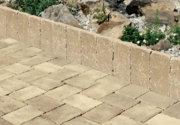 Nainstalované betonové obrubníky vedle dlažby v zahradním prostředí.