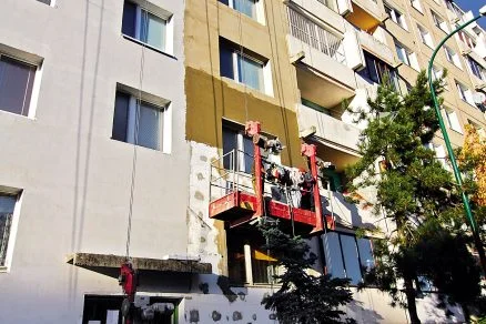 Práce na fasádě s použitím polystyrénu při rekonstrukci bytového domu.