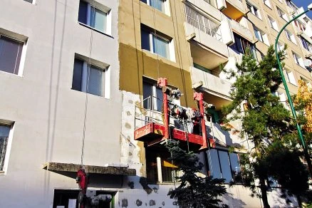 Práce na fasádě s aplikací žlutého polystyrenu.