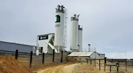 Velké bílé silo pro výrobu betonu na průmyslovém areálu.