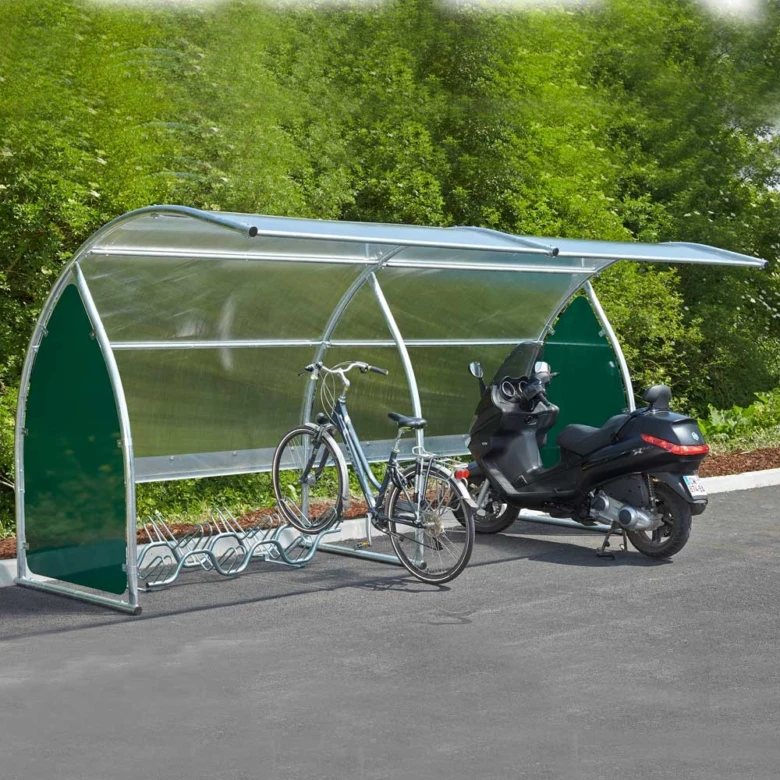 Přístřešek pro kola s motocyklem na pozadí zelených keřů.