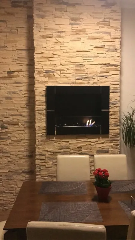 Moderní plynový krb bez komínu v kamenné zdi.