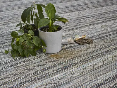 Rostliny v květináčích na vzorovaném balkónovém koberci.