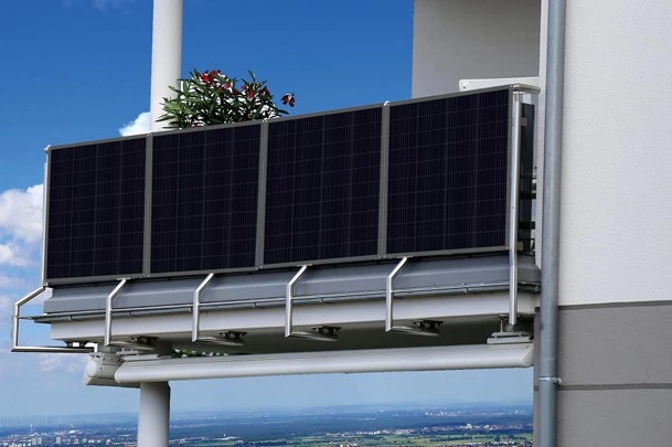 Fotografie fotovoltaických panelů na balkóně s kvetoucími rostlinami.