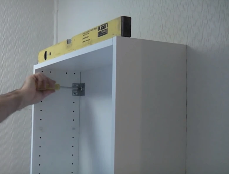 Zavěšení horní skřínky pomocí šroubováku s úrovně na stropu.