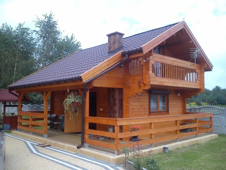 Dokončená dřevěná chata s terasou a balkónem.
