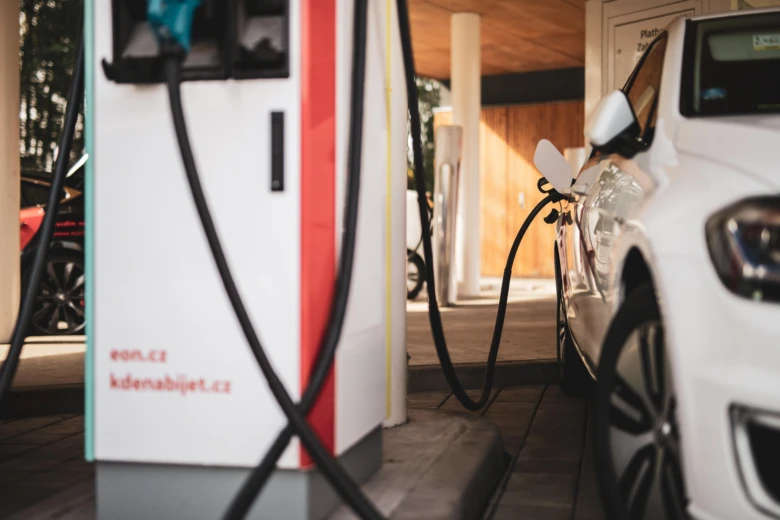 Bílé elektromobil nabíjený na veřejné stanici pro elektrická vozidla.