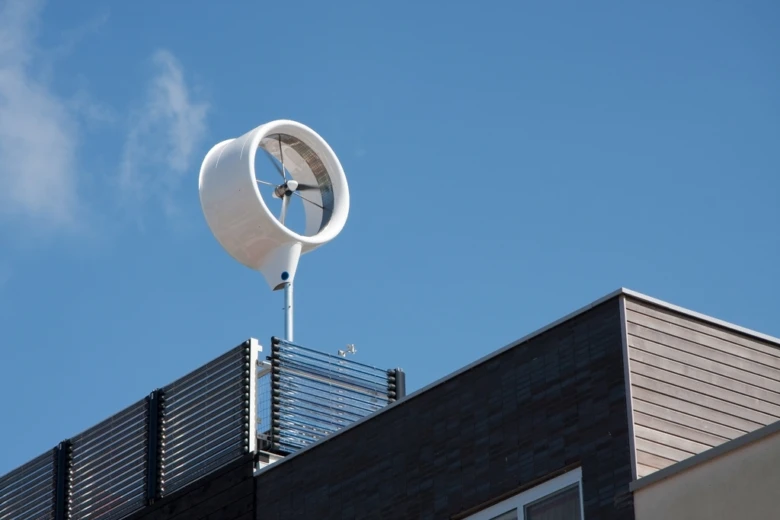 Bílá mikro větrná elektrárna na střeše domu.