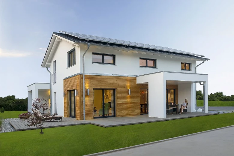Moderní dřevostavba s bílými fasádami a solárními panely na střeše.