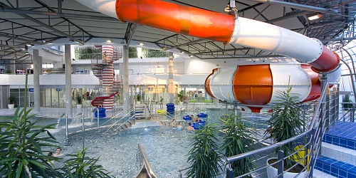 Vnitřní aquapark s vodními skluzavkami a bazénem.