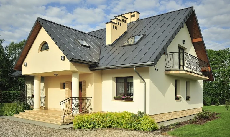 Moderní dům s plechovou střešní krytinou na pozadí zeleně.