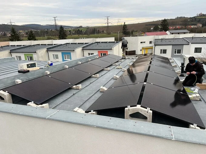 Montáž fotovoltaických panelů na střechu budovy.