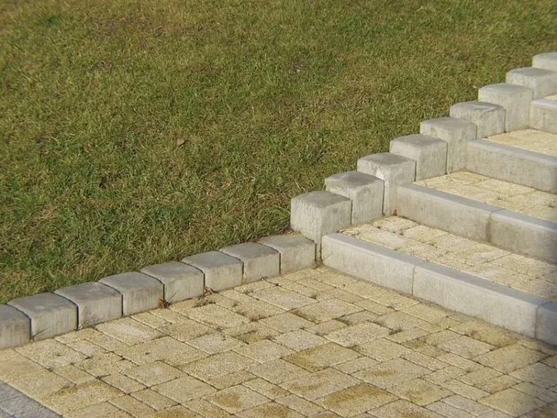 Hotový schodiště z dlažebních kostek s kamenným lemem na trávníku.