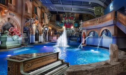 Indoor water park pool area with fountain and piano