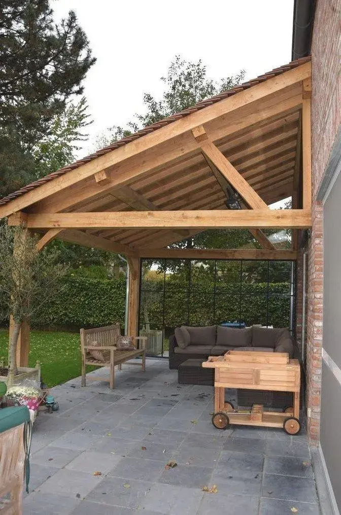 Dřevěná pergola u domu s venkovním posezením.