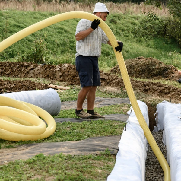 Muž manipuluje s žlutou hadicí pro odvod dešťové vody.