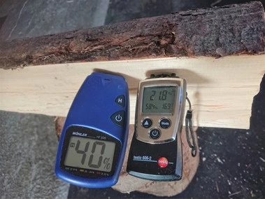 Dva vlhkoměry na kusu dřeva ukazující obsah vody v procentech.