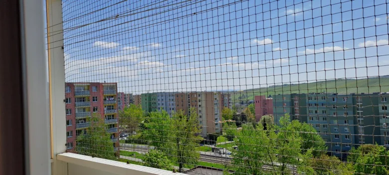 Záchytná síť na balkóně s výhledem do města.