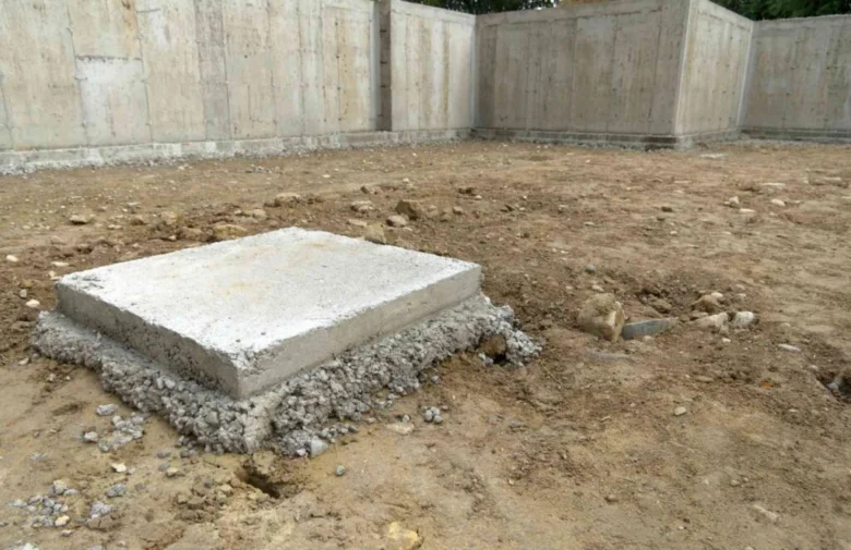 Čerstvý betonový základní patka pro dřevostavbu na štěrkovém loži.