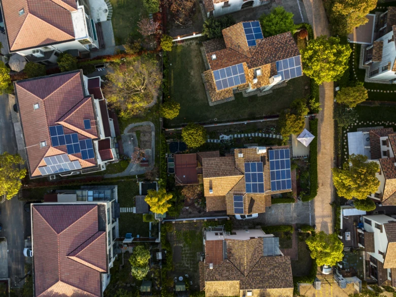 Vzdušný pohled na domy s fotovoltaickými panely na střechách.