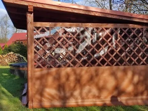 Dřevěná pergola s mřížkovou plachtou pro zahradní úkryt.