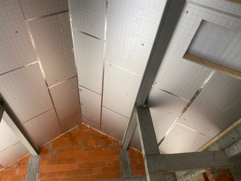 Bílá deska tepelné izolace z materiálu PIR nainstalovaná na stropě.