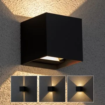 Moderní černá venkovní svítidlo na zdi osvětluje pergolu.