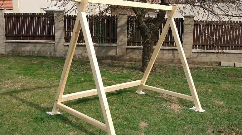 Dřevěná konstrukce houpačky na zahradu postavená z prken.