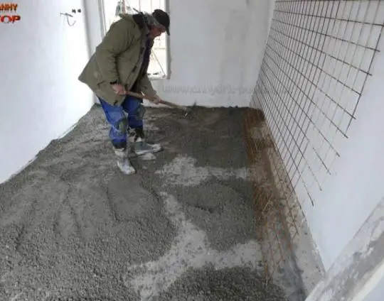 Pracovník nalévá betonovou desku pro hydroizolaci základové plochy.