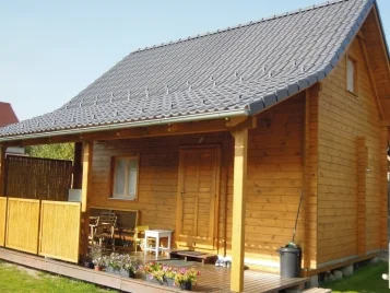 Drevená chata s terasou a zahradním nábytkem po dokončení.