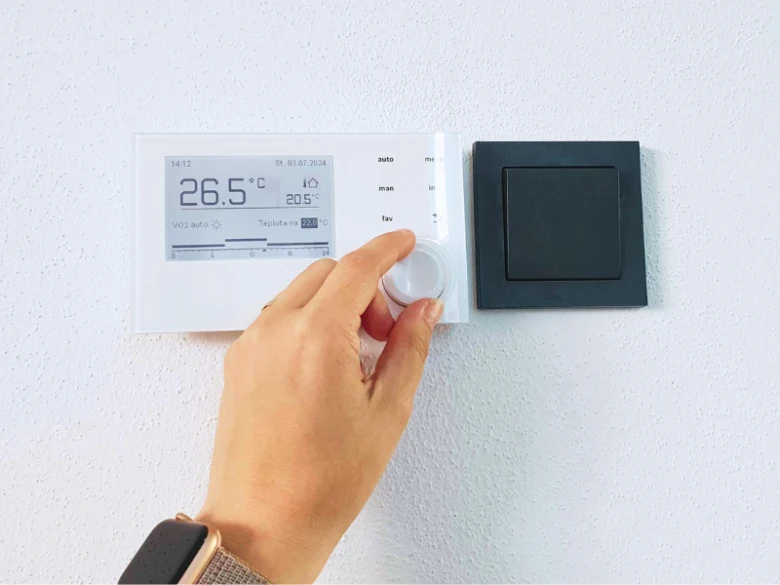Ruka nastavuje chytrý termostat pro úsporu energie v domácnosti.