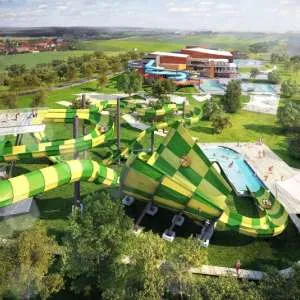 Zeleno-žluté vodní skluzavky v bazénovém centru s okolními bazény.