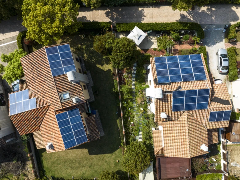 Dvě rodinné domy s fotovoltaickými solárními panely na střechách.