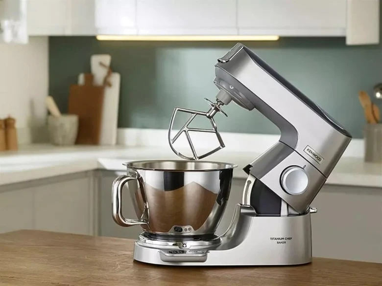 Stříbrný kuchyňský robot s mýdlovým míchacím nástavcem na dřevěném povrchu.