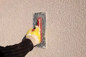 Hand applying plaster to wall