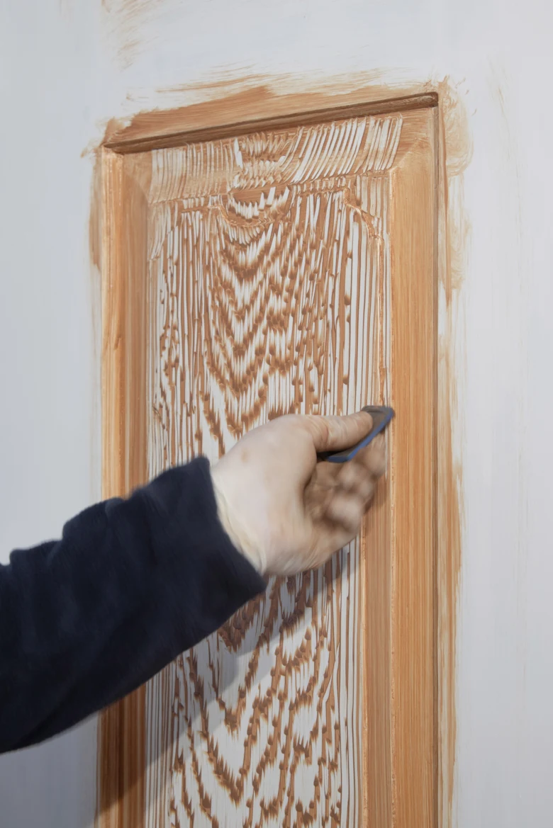 Nanášení dřevotvarové hmoty na dveřní panel pomocí stěrky.