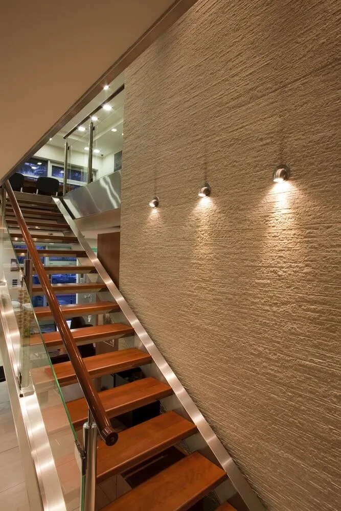 Moderní schodiště s dřevěnými stupni a LED svítidly na zdi.