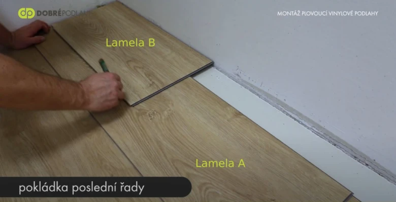 Muž pokládá vinylovou podlahu u zdi pro poslední řadu.