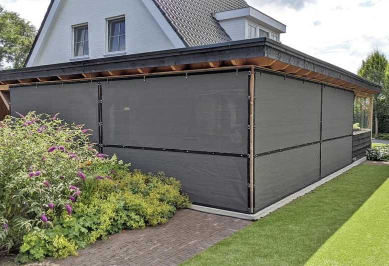 Moderní pergola s tmavou plachtou na zahradě domu.
